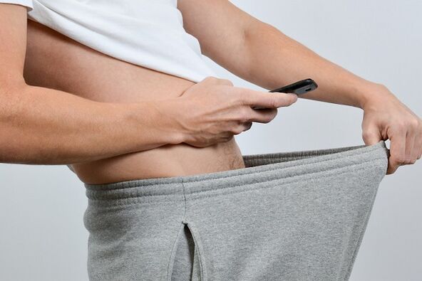 رجل ينظر تحت سرواله إلى القضيب المتضخم